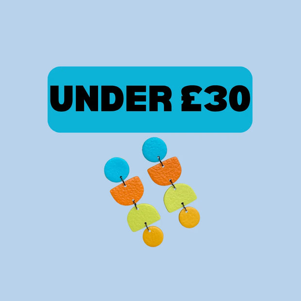 A pair of colorful geometric drop earrings with blue, orange, yellow, and green pieces, displayed below a bright blue banner that reads 'UNDER £30' on a light blue background.