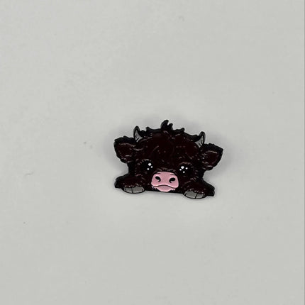 Black cow pin badge on a light gray background