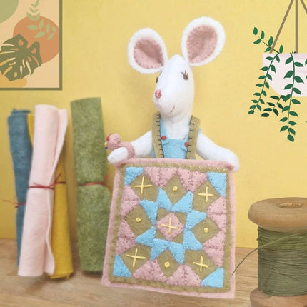 Stuffed mouse toy with a quilt on a yellow background