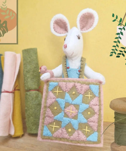 Stuffed mouse toy with a quilt on a yellow background