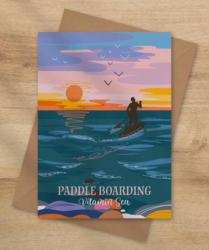 Greeting card with paddle boarding design on a wooden surface